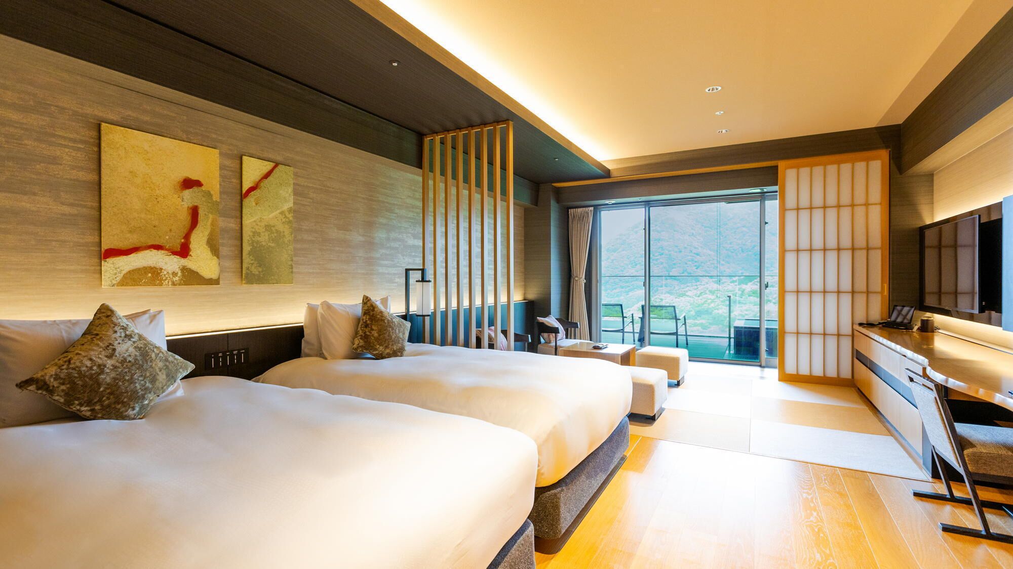Et moderne hotelværelse med to senge, et skrivebord og et stort vindue med udsigt.