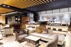 Un moderno vestíbulo de hotel con sofás, sillones y una zona de bar.