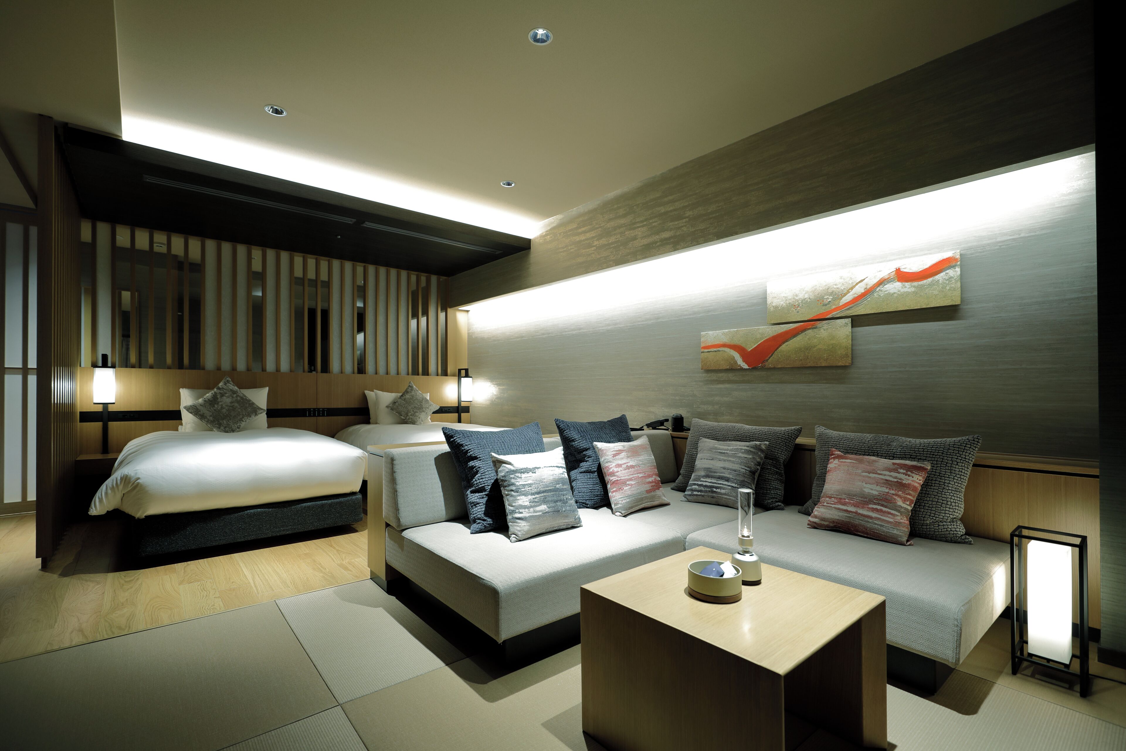 A modern hotel room with a bed, sofa, and a small table.