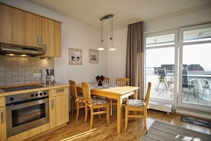 Une cuisine moderne avec des meubles en bois, un four encastré et un coin repas comprenant une table et des chaises.
