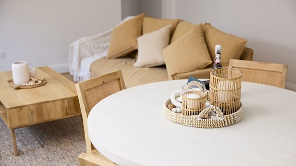 A cozy living room with a round white table, a wooden side table, and a beige sofa with cushions. - Two-bedroom apartment nestled at the foot of the iconic Bondi Beach (Bondi)