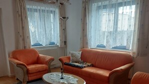 A living room with a sofa, two armchairs, a coffee table, and a chandelier. - Vacation apartment in Liegau Augustusbad (Radeberg)