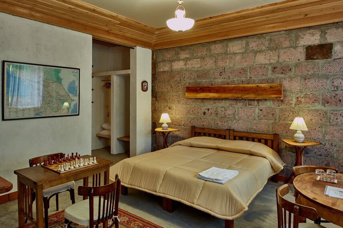 A room with a bed, a wooden table with chess set, and a map on the wall.