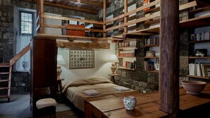 A rustic room with a wooden bed, a desk, and bookshelves filled with books. - Villa Kars (Gyumri)