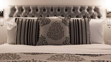 A bed with a tufted headboard, striped pillows, and a patterned throw.