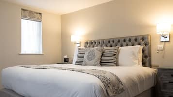 A neatly made bed with a tufted headboard, bedside lamps, and a bedside table with a tissue box.