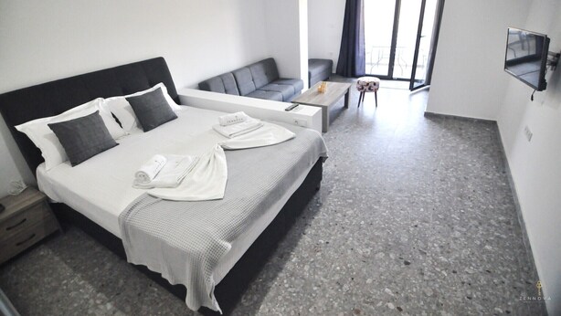 Une chambre d’hôtel avec un lit, un canapé, une table basse et un téléviseur.
