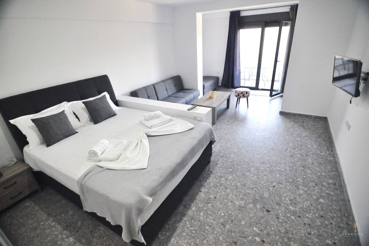 A hotel room with a bed, a sofa, a coffee table, and a TV.