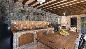 Une cuisine rustique avec un mur en pierre, des armoires en bois et une grande table en bois.