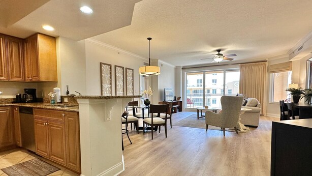 A spacious living area with a dining table, a sofa, and a kitchen area with wooden cabinets and a granite countertop. - Belle Harbor  803-M - Panoramic Views (Clearwater Beach)