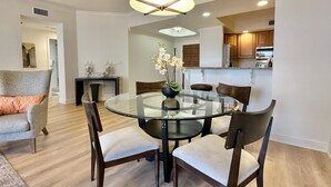 A dining area with a glass table and chairs, a pendant light, and a vase with flowers. - Belle Harbor  803-M - Panoramic Views (Clearwater Beach)