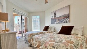 A hotel room with two beds, a wicker side table, a ceiling fan, and a large window with blinds. - Belle Harbor  803-M - Panoramic Views (Clearwater Beach)
