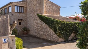 Un edificio de piedra con techo de tejas, una ventana pequeña y una planta en maceta.
