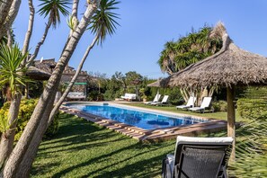 A pool area with lounge chairs and a thatched umbrella. - Ca'n Suau Filasop by Rentallorca (Son Macià)