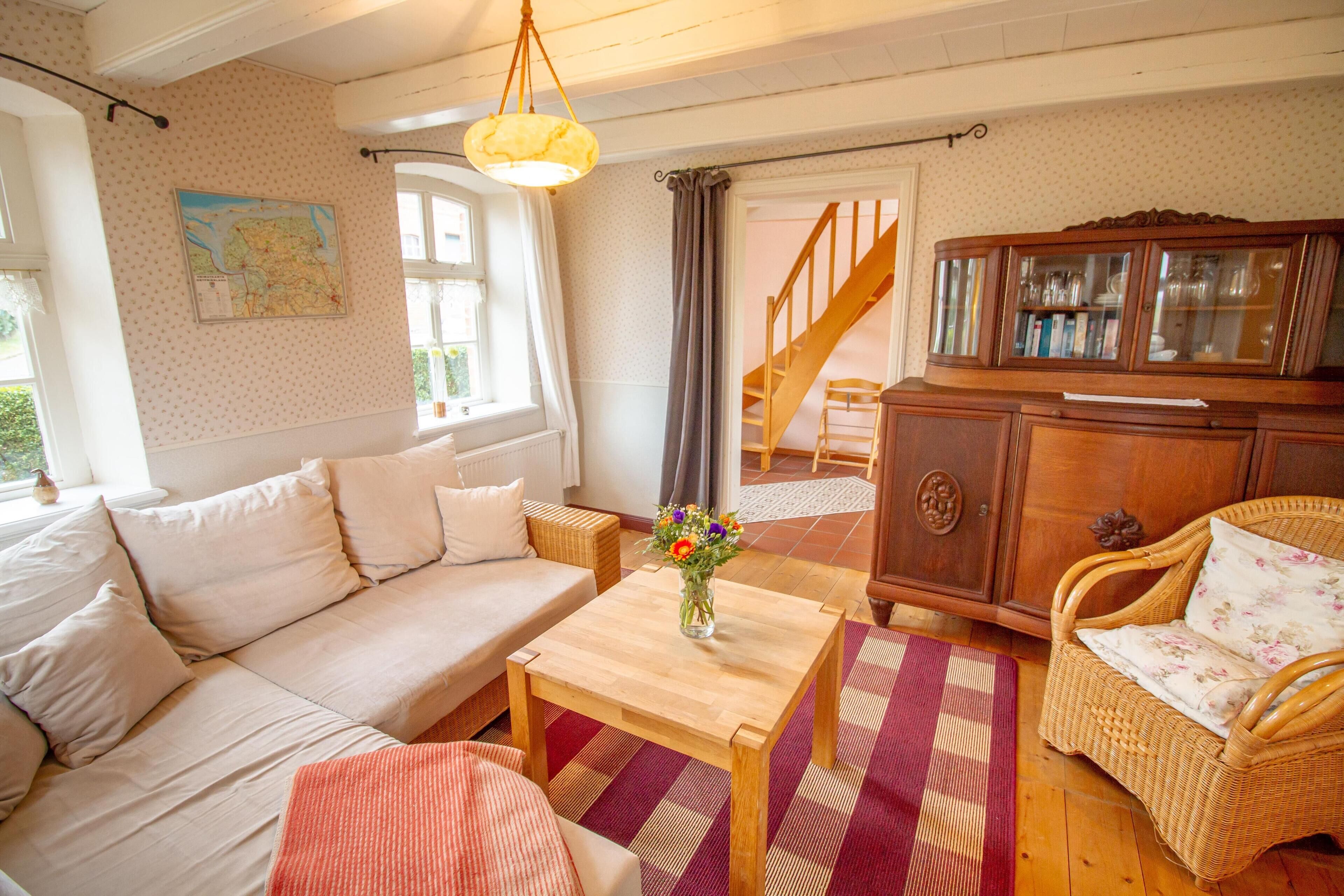 A cozy living room with a sofa, a wooden coffee table, a wicker armchair, and a cabinet.