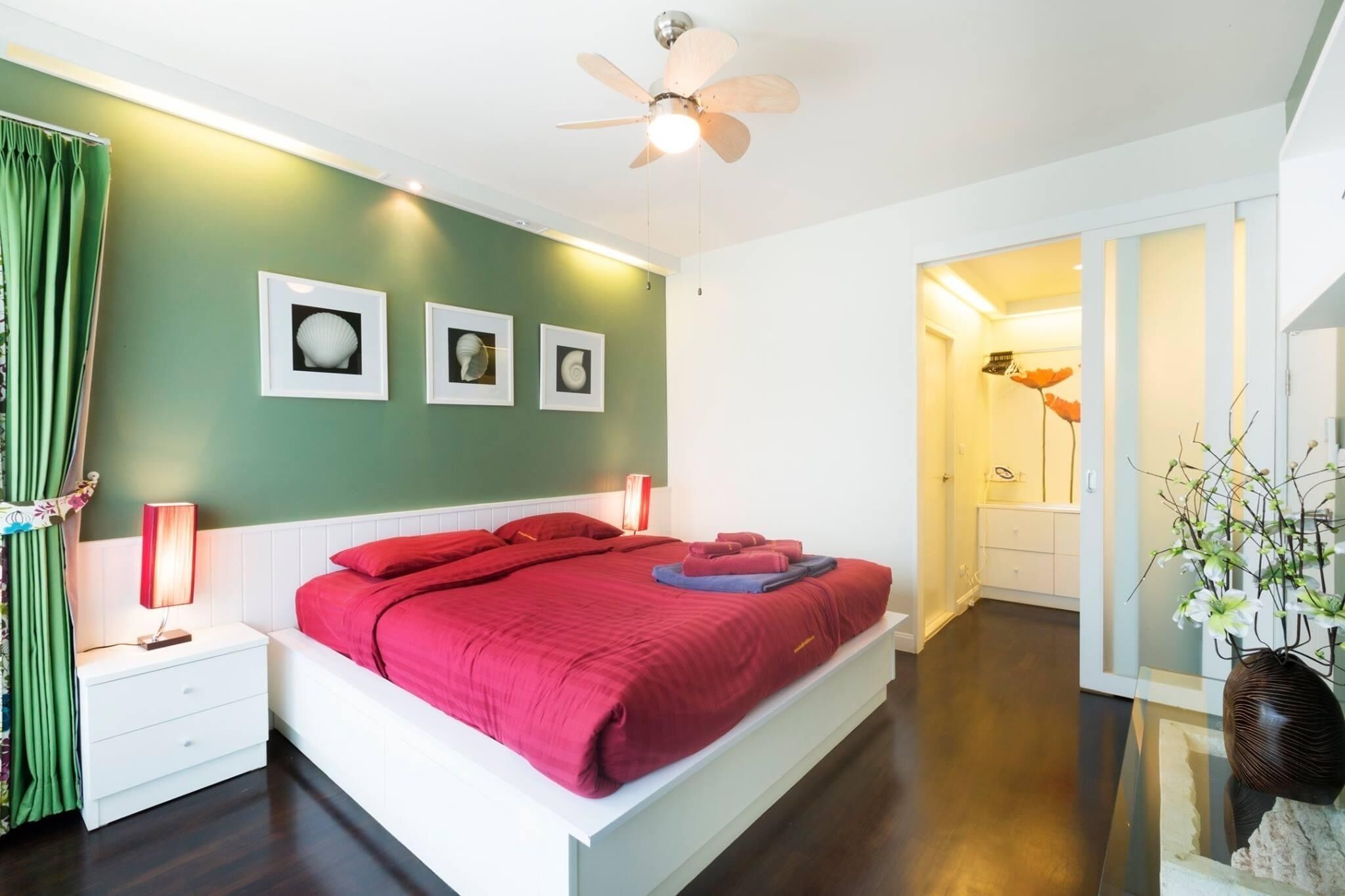 A modern bedroom with a large bed, green walls, and framed pictures.