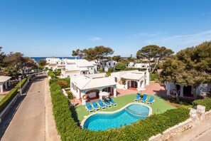 Un resort con piscina, sillas de descanso y vista al mar.