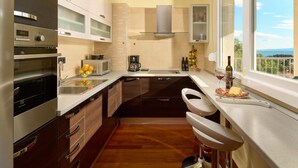 A compact kitchen with modern appliances, a built-in oven, microwave, and a coffee maker. There is a window with a view of the outdoors. - Sun Spalato Hills 7 (Split)