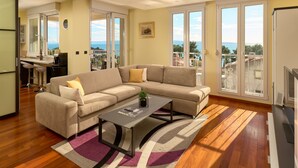 A modern living room with a sectional sofa, a coffee table, and a view of the sea through large windows. - Sun Spalato Hills 7 (Split)