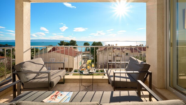 A balcony with two sofas and a small table with a drink and a plate. - Sun Spalato Hills 7 (Split)