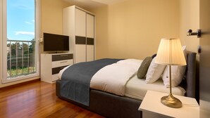 A bedroom with a bed, a TV, a wardrobe, and a balcony. - Sun Spalato Hills 7 (Split)