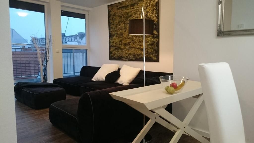 A modern living room with a sofa, a small table with fruit, and a floor lamp.