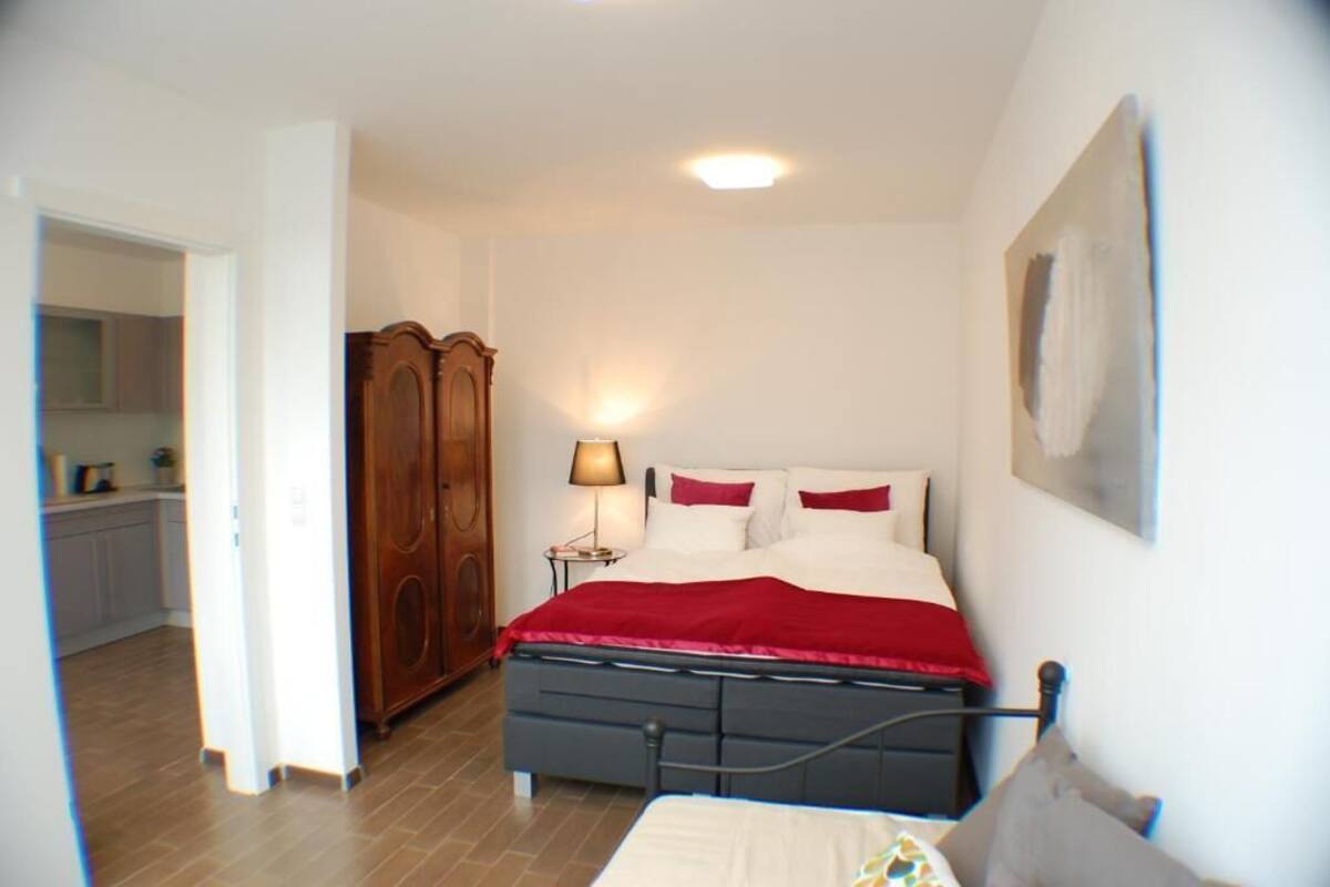 A bedroom with a bed, a nightstand, a lamp, and a wardrobe.