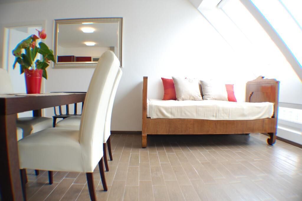 Ein Zimmer mit einem hölzernen Bett, einem Esstisch mit Stühlen, einer Zimmerpflanze und einem Spiegel an der Wand.