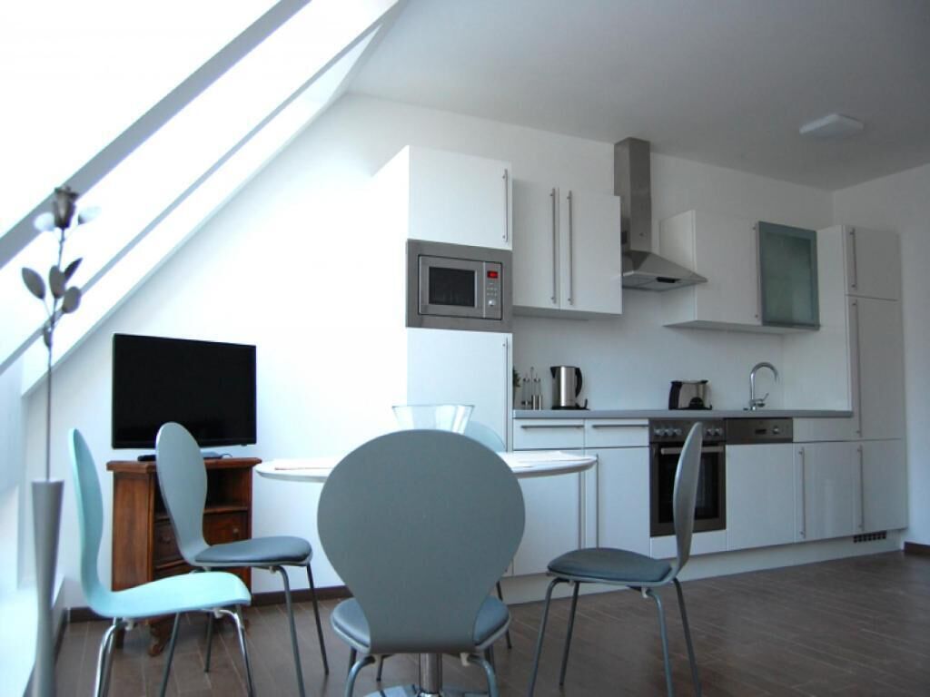 Une cuisine moderne avec des meubles blancs, un four à micro-ondes, une cuisinière et un lave-vaisselle. Il y a également un coin repas avec une table et des chaises.