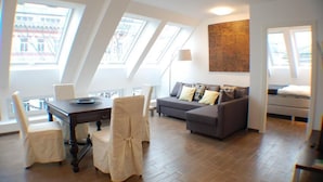Un salon moderne avec un coin repas, de grandes fenêtres et un plafond de style industriel.