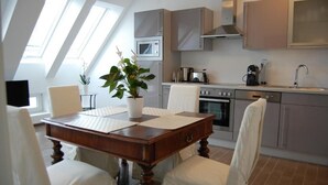 Une cuisine moderne avec un coin repas, comprenant une table en bois, des chaises blanches et une plante en pot.
