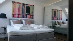 Une chambre à coucher moderne avec un lit, une table de chevet, une lampe et un grand miroir.