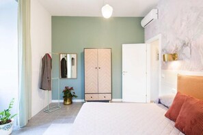 A bedroom with a bed, a wardrobe, a mirror, and a potted plant. - Luxury Apartment Zona Vaticano-Prati (Roma)