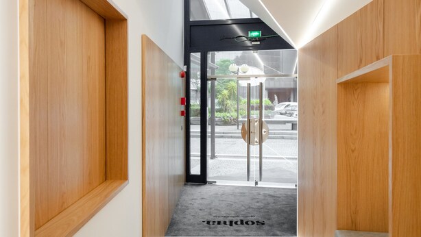 A modern reception area with a glass door, wooden paneling, and a carpet with the word "reception". - Sophia Oporto Urban Suites (Porto)