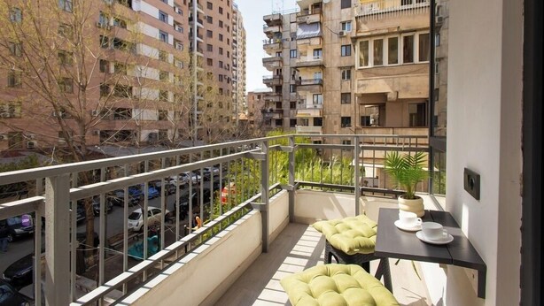A balcony with a table and chairs, a potted plant, and a view of surrounding buildings. - Stay Inn on Pushkin Street 43 (Yerevan)