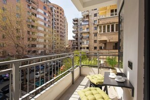 A balcony with a table and chairs, a potted plant, and a view of surrounding buildings. - Stay Inn on Pushkin Street 43 (Yerevan)