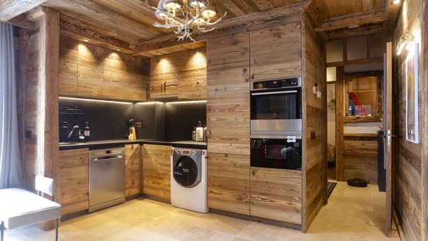 Una cocina moderna con paneles de madera, electrodomésticos integrados y una araña.