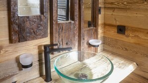 Un baño con paneles de madera, un lavabo de cristal y dos espejos.