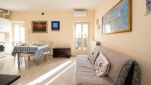 Una sala de estar con un sofá, una mesa de comedor con sillas, una lavadora y una puerta que da al exterior.