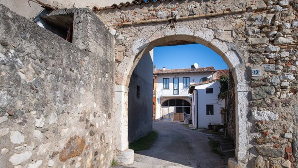 Un arco de piedra que da paso a una calle estrecha flanqueada por edificios.