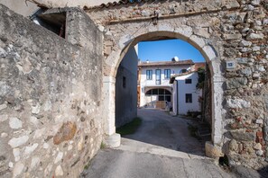 A stone archway leading to a narrow street with buildings on either side.