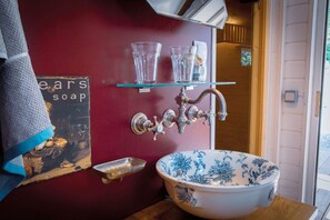 A bathroom with a vintage-style sink, a red wall, and a towel hanging on the left.