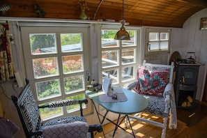 Enjoy a peaceful retreat with a view of the surrounding greenery from the large window, featuring a small table and a vintage stove.