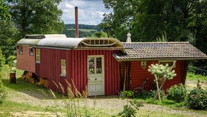 Una casa di legno rossa con una porta bianca, un piccolo portico e un camino.