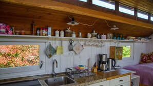 Una cucina con piano di lavoro in granito, lavello in acciaio inossidabile e macchina da caffè. Presenti armadietti sotto il piano e una finestra con vista sul verde.