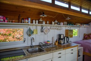 Enjoy a well-equipped kitchen with a stainless steel sink, dishwasher, and coffee maker, offering a serene view of the lush garden.