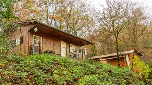 A wooden cabin with a porch, surrounded by dense foliage and trees. - Stilles Glück Helmeroth (Helmeroth)