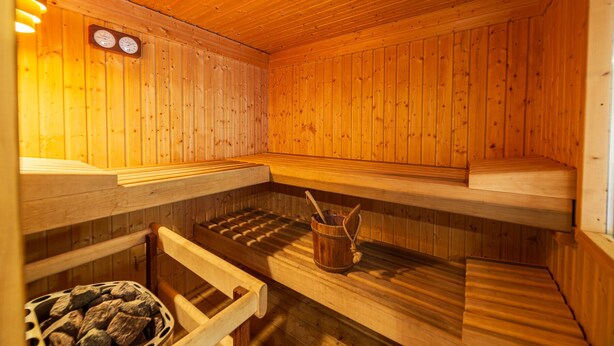 A sauna with wooden benches and a stone basin. - Stilles Glück Helmeroth (Helmeroth)