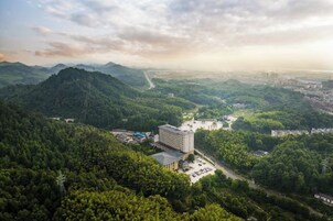A hotel surrounded by lush green hills with a clear view of the city in the distance.