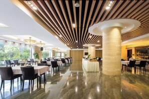 A spacious dining area with multiple tables and chairs, a polished marble floor, and a modern ceiling design with wooden slats and recessed lighting. - Nanyue Resort (Huoshan)